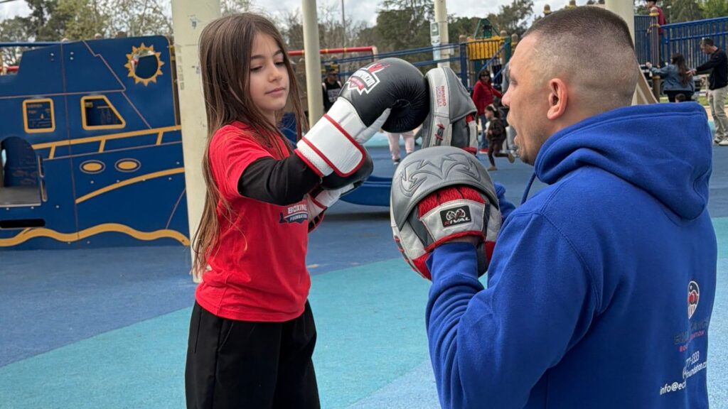group of diverse kids warming up for outdoor boxing class